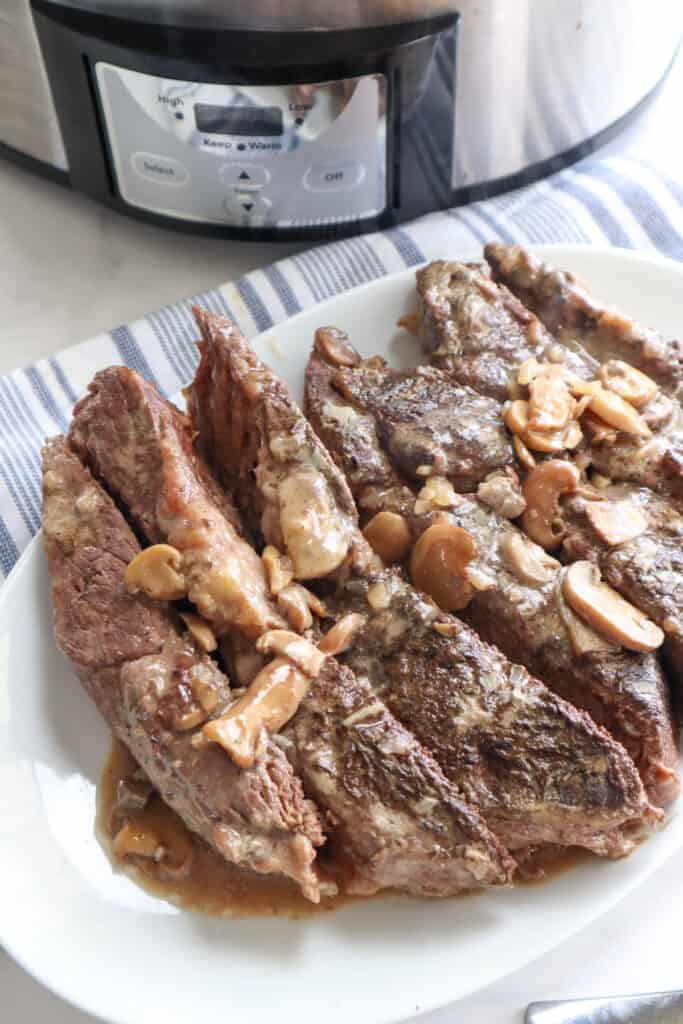 slicked beef on a white plate made in slow cooker