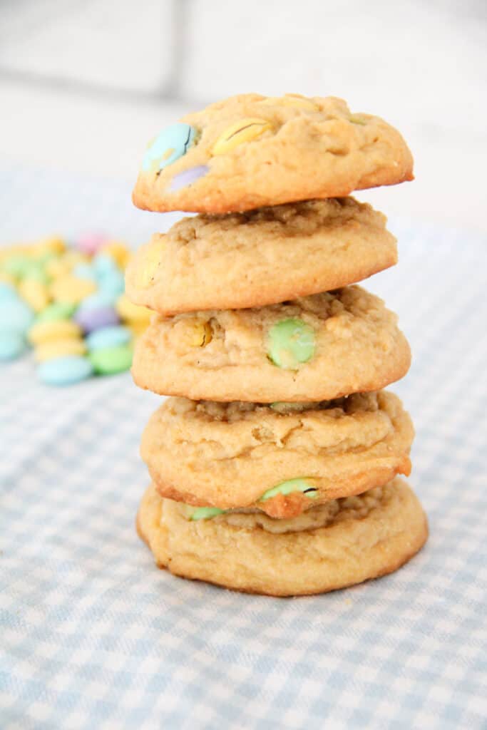 stacked Easter M&M cookies with a pile of pastel chocolate candies in the background