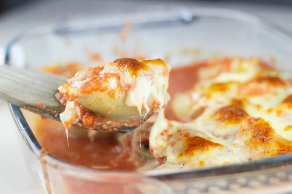 a single stuffed shell with ricotta and baby spinach on a wooden spatula