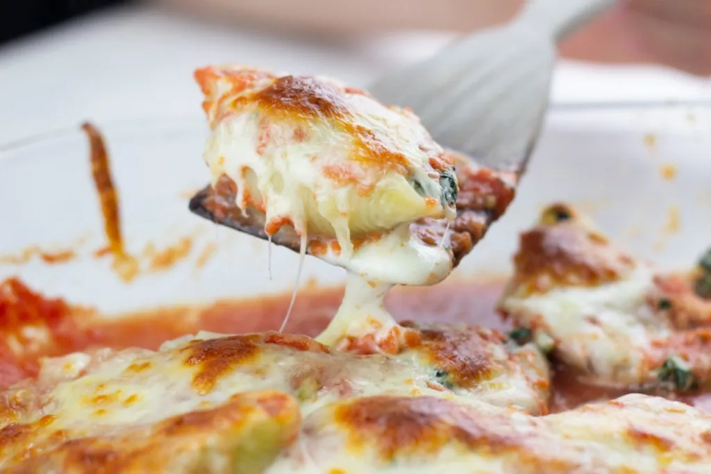 spinach and ricotta cheese stuffed shell on a wooden spoon