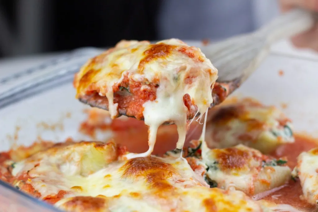 a dish full of homemade ricotta and spinach stuffed jumbo shells baked in the oven with melted cheese