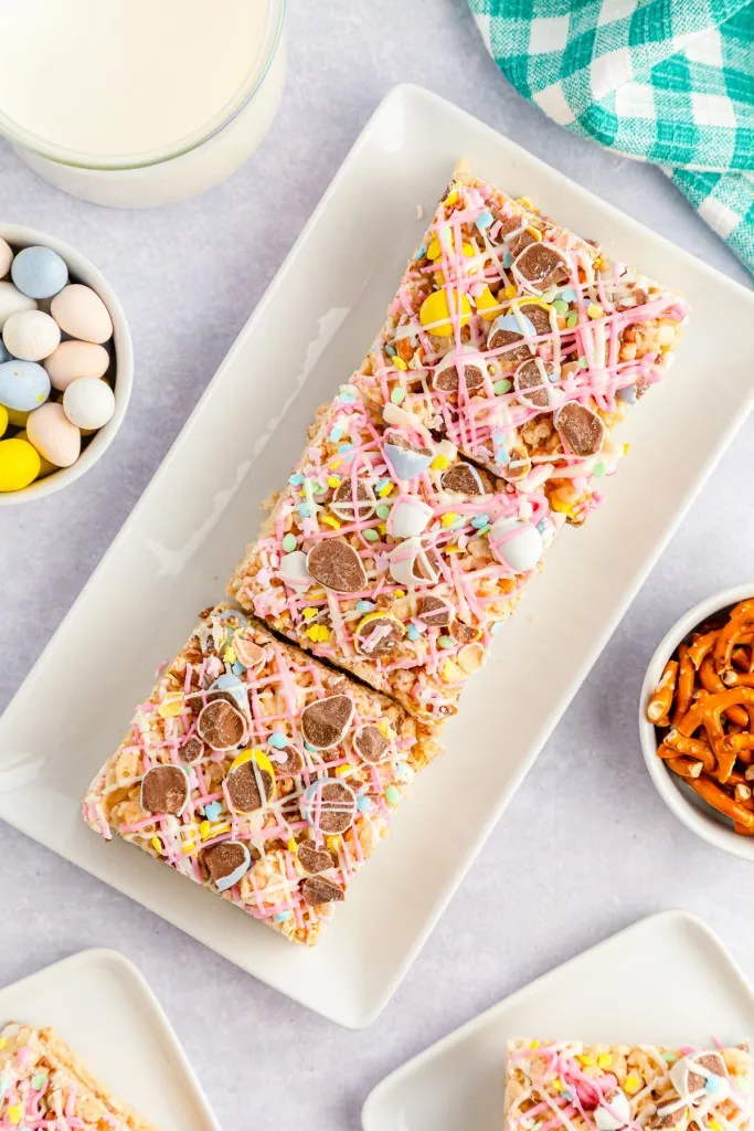 Cadbury Mini Egg Rice Krispies Treats on a rectangular white plate with drizzled chocolate on top