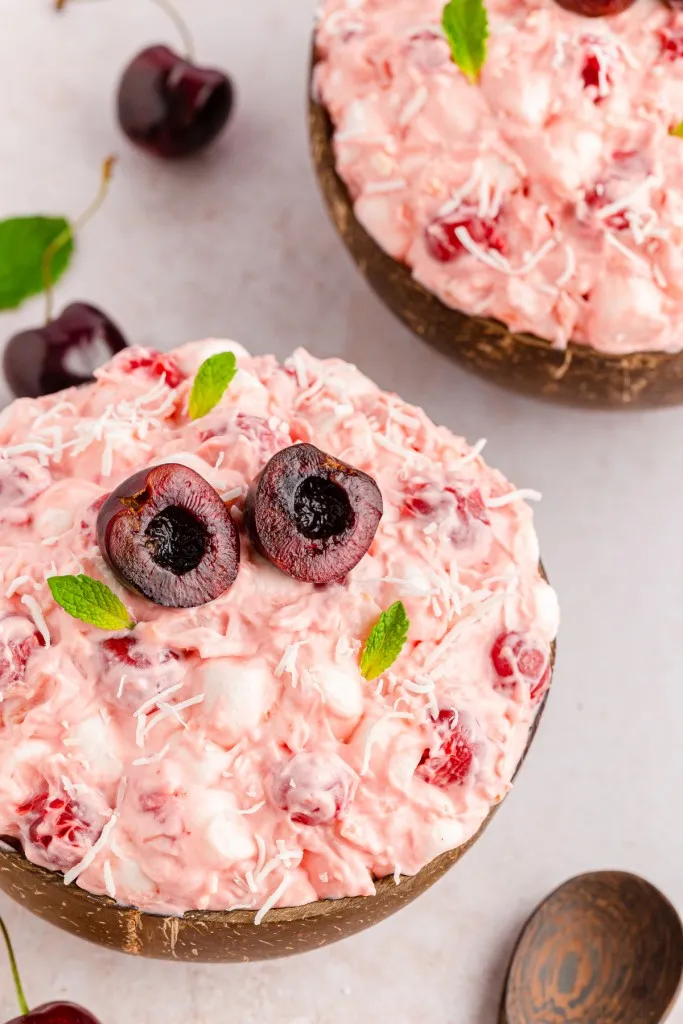 two bowls full of cherry flow salad piled high into mounds. Served with sliced fresh red cherries in half on top with fresh mint