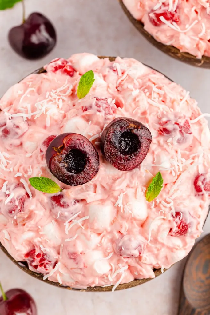 a fresh bowl of cherry fluff salad with sliced cherries and sprigs of mint on top and served in wooden bowls
