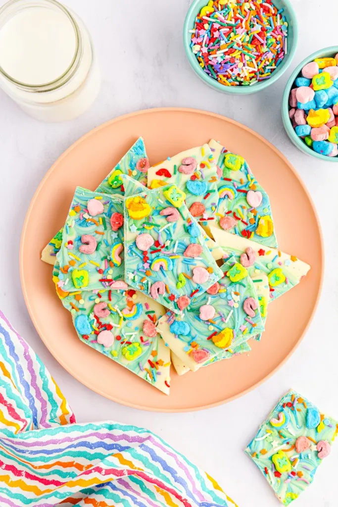 lucky charm bark stacked on a peach colored plate and rainbow napkin