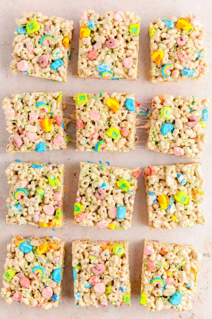 9 lucky charms treats bars cut into squares on a light pink slab background