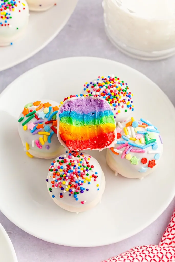 overhead shot of a rainbow cake ball with a bite mark to show the layers of colors. 