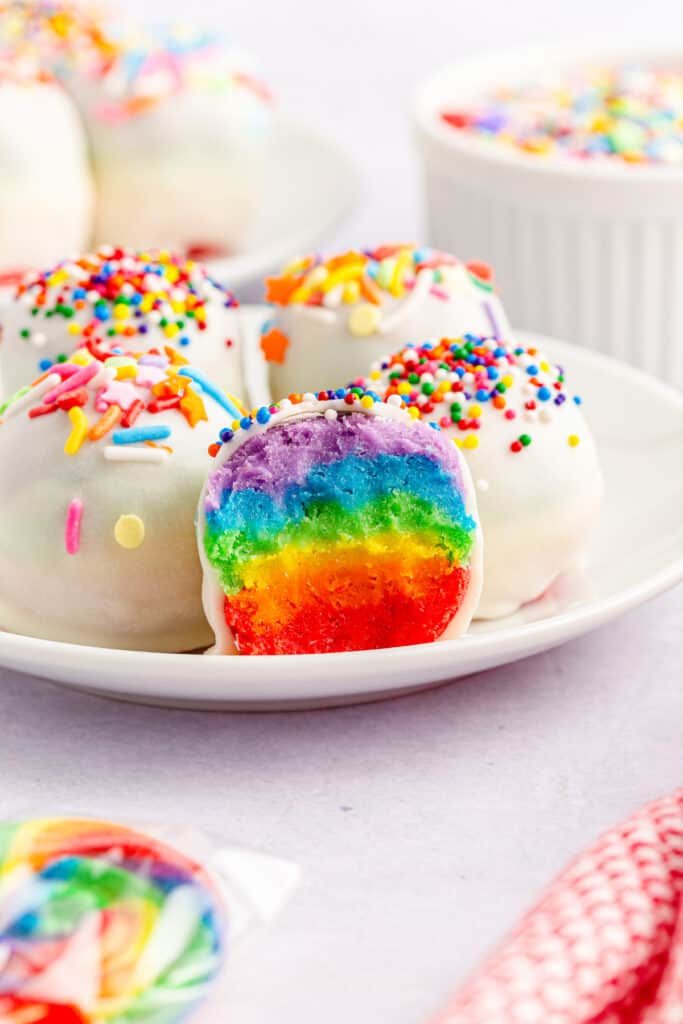 close up view of a bite taken out of a rainbow cake mix ball