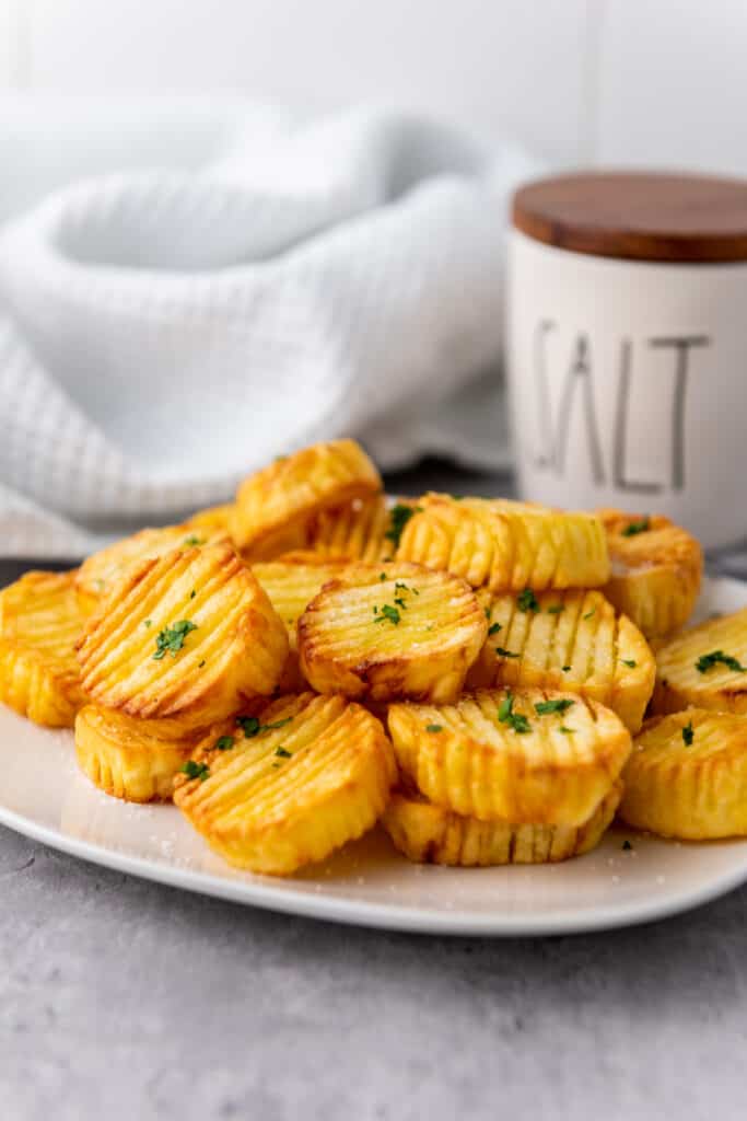 side view of air fryer accordion potatoes with sea salt on a white plate