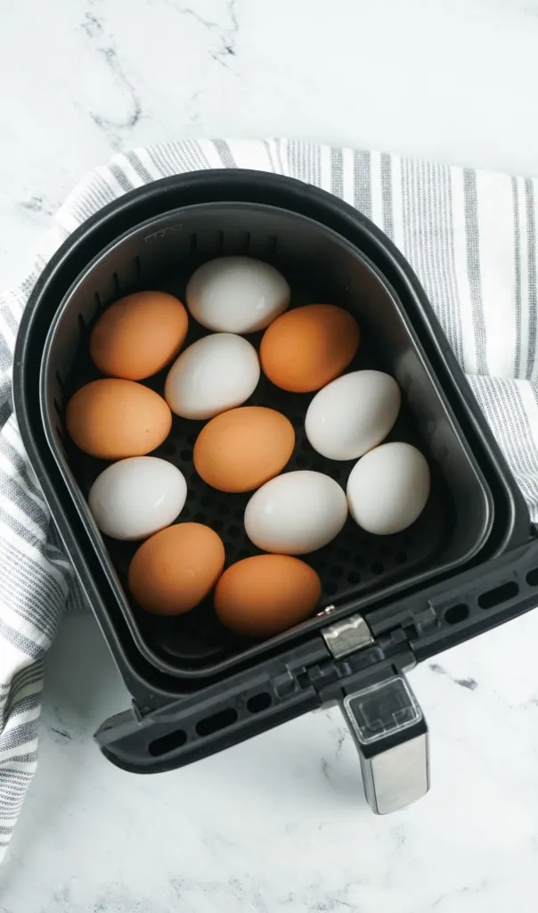 white and brown eggs in an air fryer basket