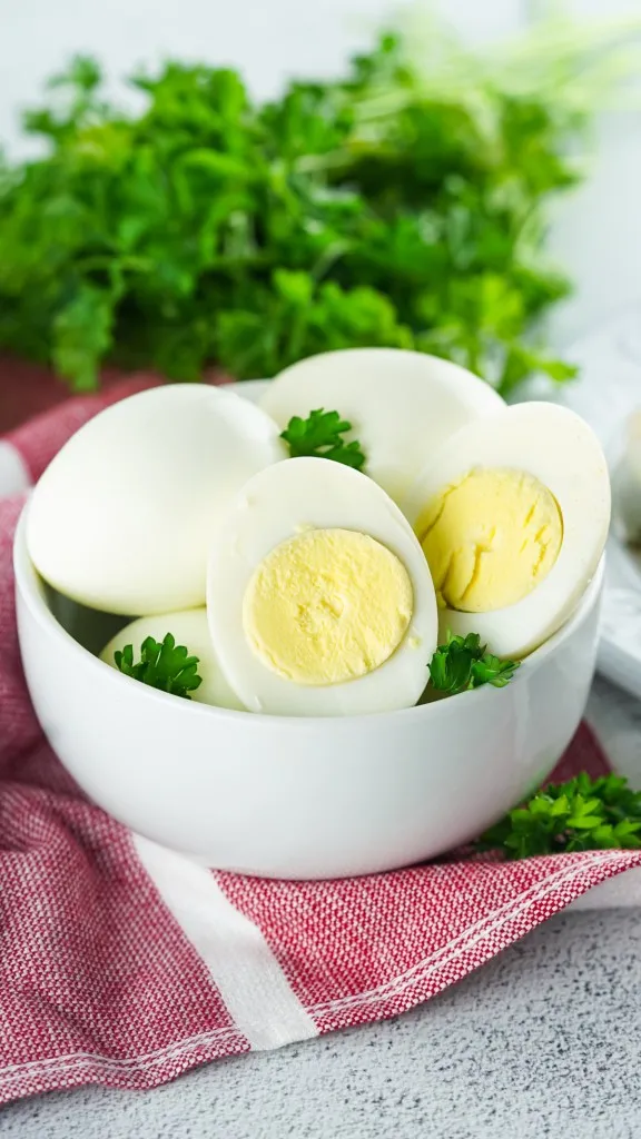 sliced hard boiled egg open to show yolk in white bowl with green parsley