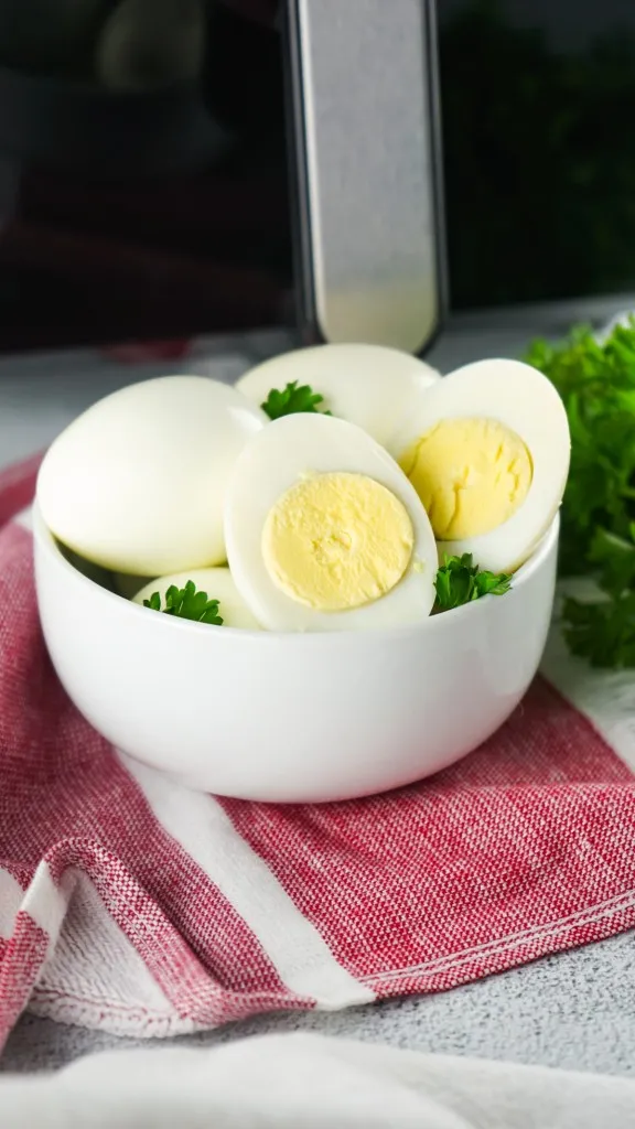 front facing view of hard boiled eggs in front of an air fryer with fresh parsley