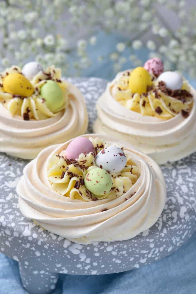 easy to make meringue easter birds nests on a blue and white speckled cake stand