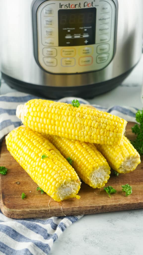 corn on the cob on a wooden board in front of an Instant Pot