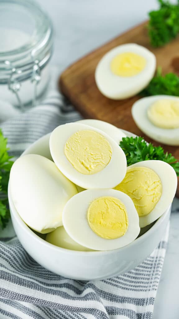 overhead show of instant pot boiled eggs in a white bowl on a gray and white napkin