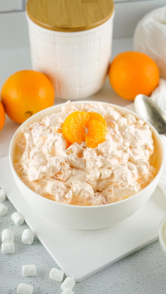side view of a cream and delicious orange fluff salad recipe that's perfect for the holidays with mini marshmallows around it