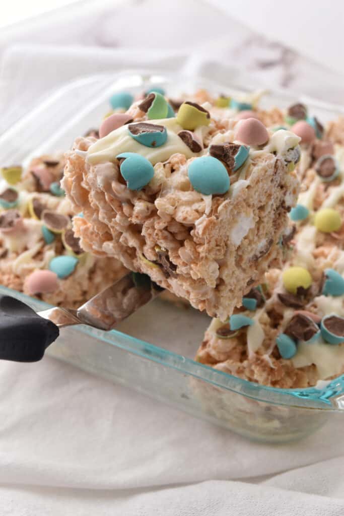 easter egg rice krispies treats in a glass pyrex pan being lifted out