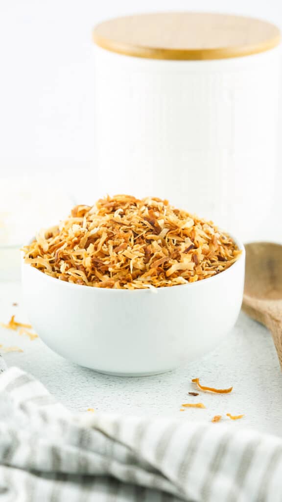 huge bowl of toasted coconut with a grey and white striped napkin