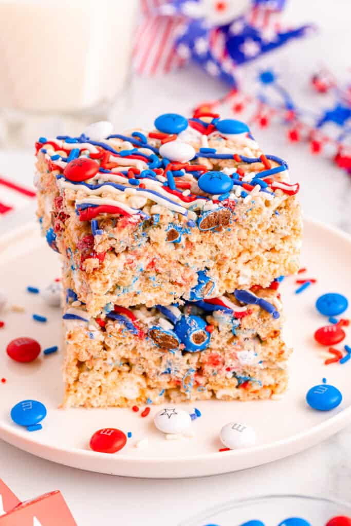 4th of july rice krispie treats stacked on each other with red, white, and blue m&ms on a white plate