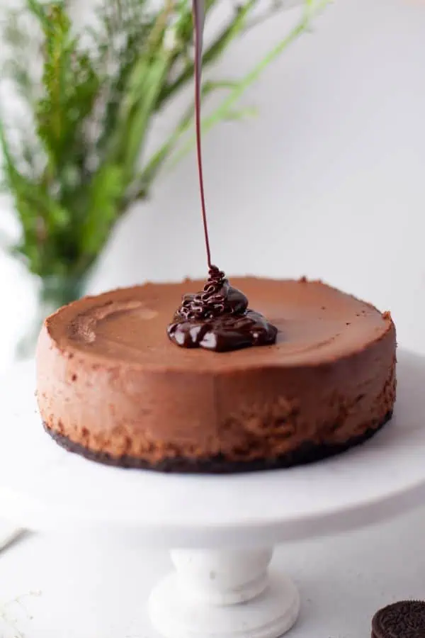 chocolate ganache pouring over top of instant pot chocolate cheesecake