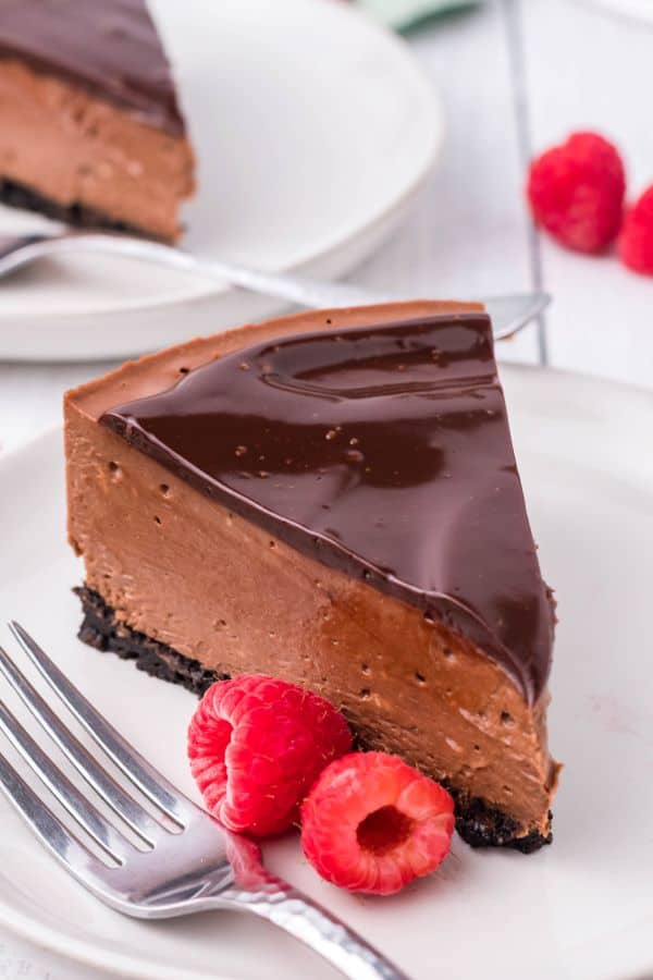 a slice of instant pot chocolate cheesecake with fresh raspberries on a white plate