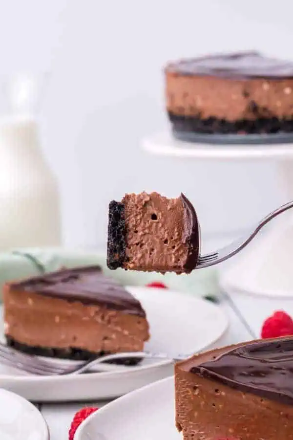 a forkful of chocolate cheesecake being held in the air