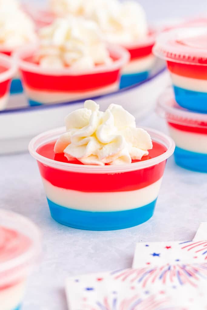 red white and blue jello shots with stacked on each other on a blue lined white plate