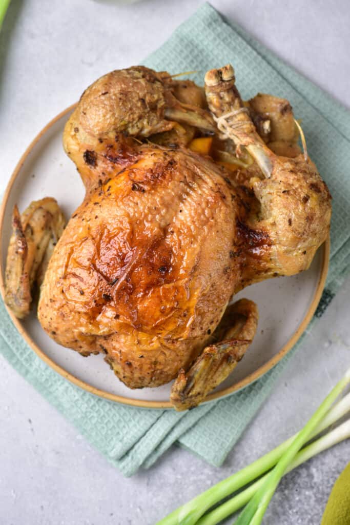 overhead shot of instant pot whole chicken on a white ceramic plate and light blue towel