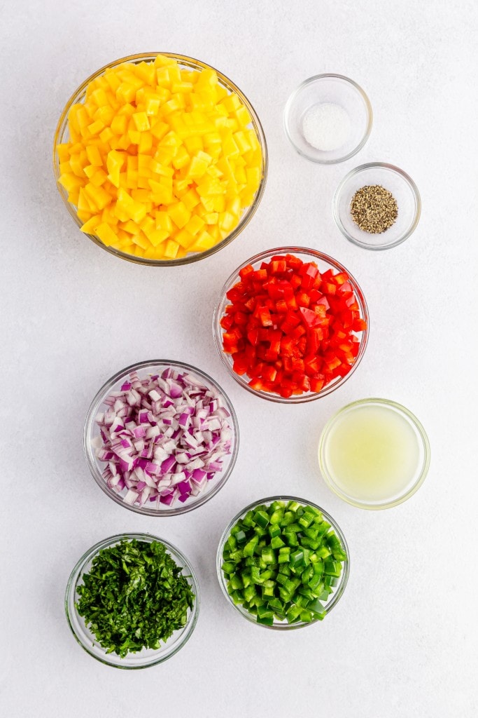 bowls of fresh cut ingredients needed to make the best summer mango salsa recipe for your tacos, meat dishes, and fish recipes.