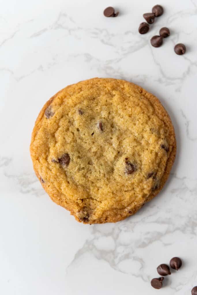 Close up of a mini chocolate chip cookie with mini chocolate chips on a marble countertop.