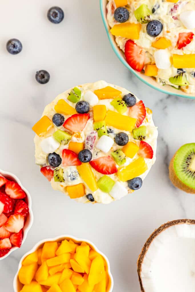 Overhead view of tropical fruit marshmallow fluff, fresh fruit on a white countertop.