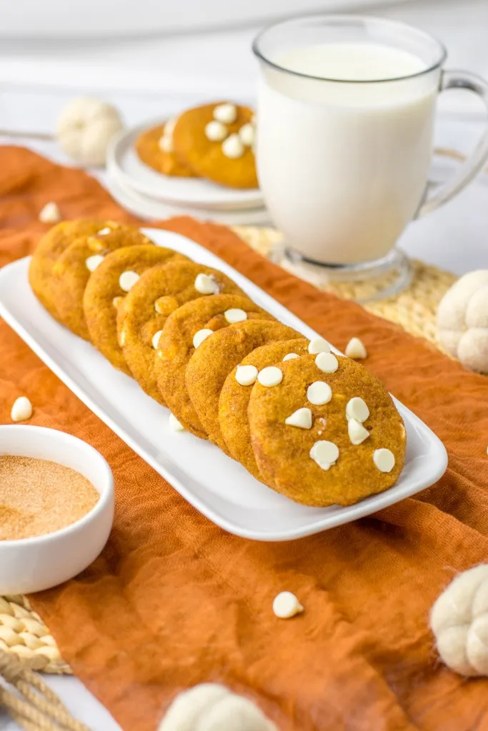 Serving tray with pumpkin snickerdoodle cookies, glass of milk, fall-inspired table decoration.