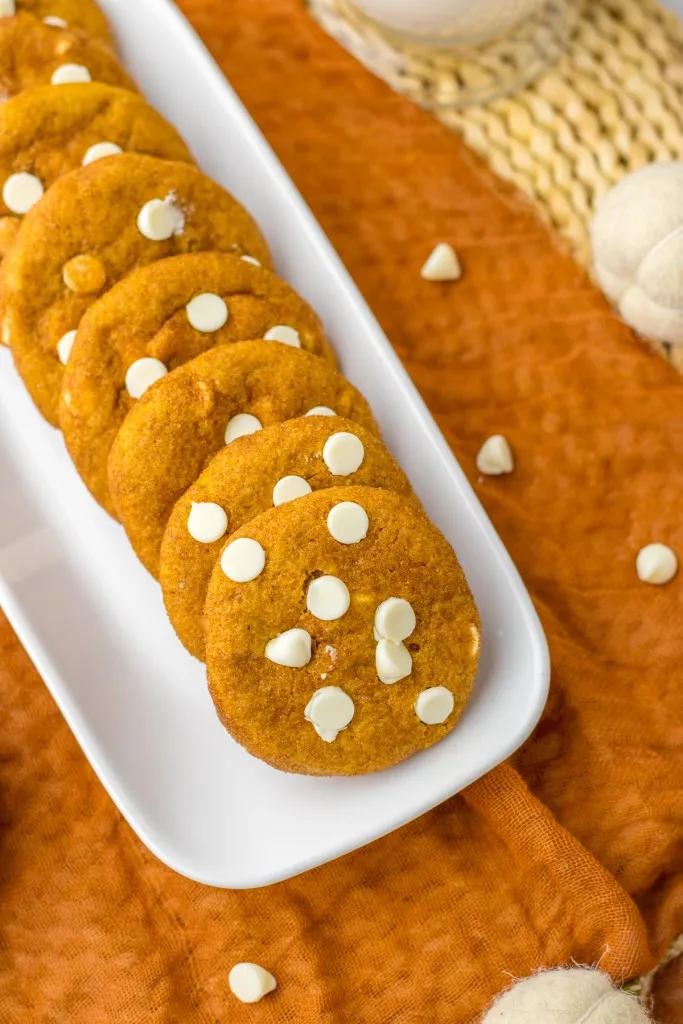Overhead view of tray with pumpkin snickerdoodle cookies on an orange table cloth.