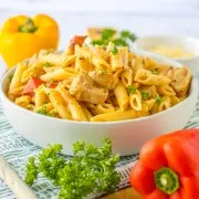 Bowl of slow cooker Cajun chicken pasta with fresh bell peppers and parsley on a countertop.