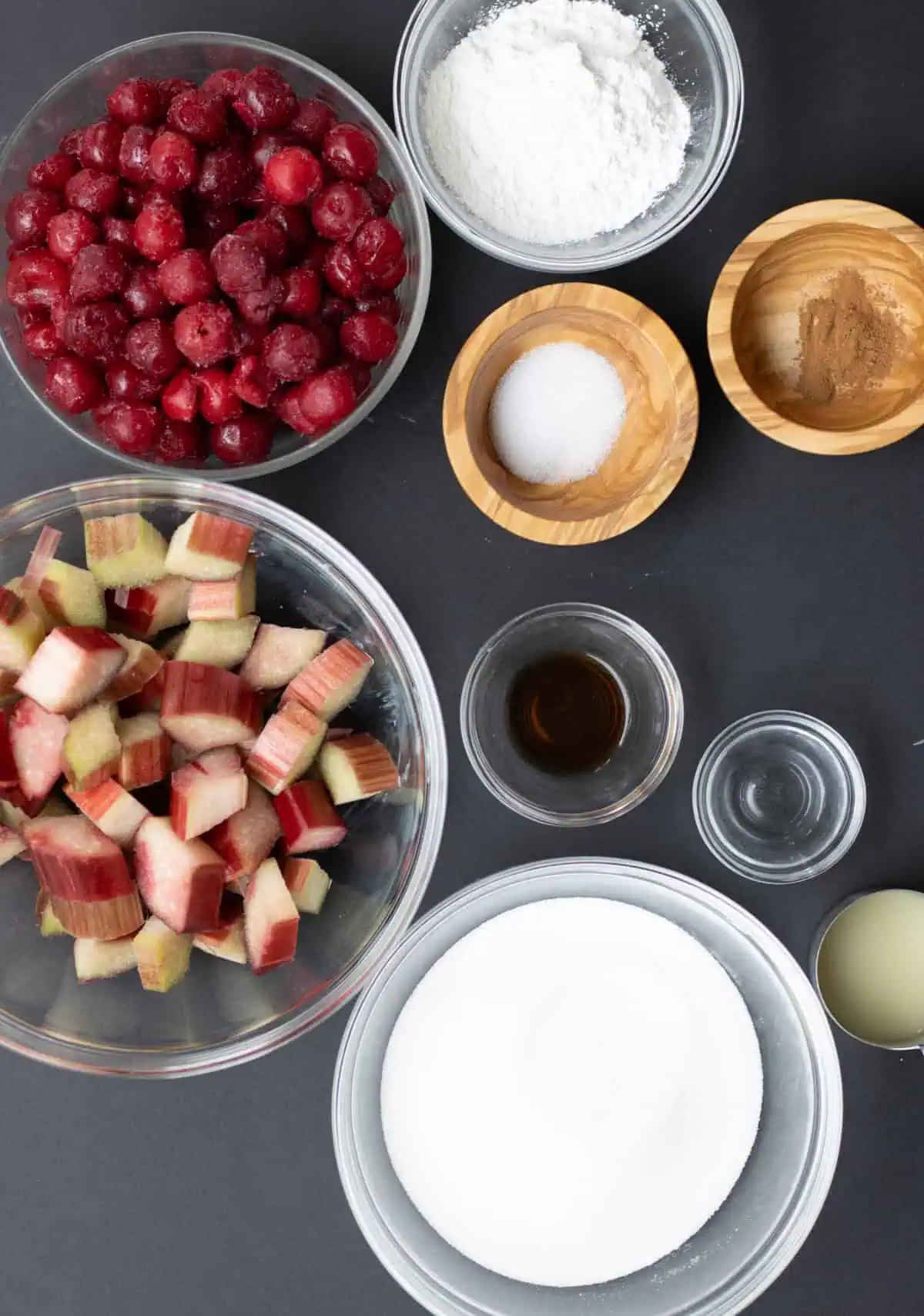 Overhead of frozen cherries, diced rhubarb, sugar, cornstarch, and pie crusts arranged for making eyeball pie