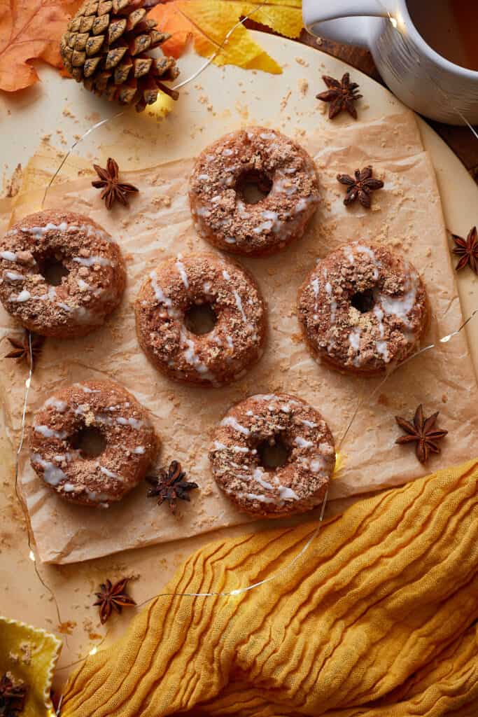 Overhead view of cinnamon roll donuts on a wooden board with fall-inspired decorations.
