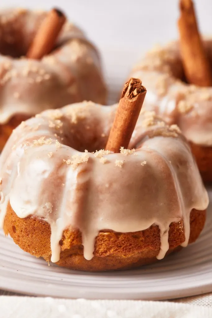 Three mini pumpkin bundt cakes on a white plate.