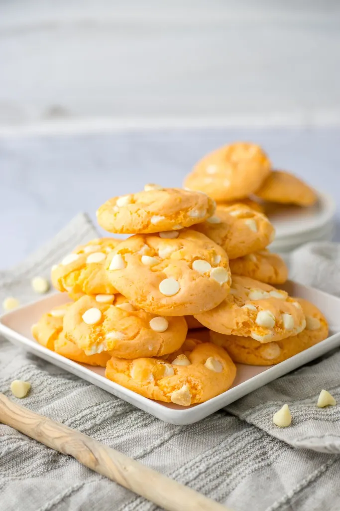 A stack of orange creamsicle cookies on a white plate.