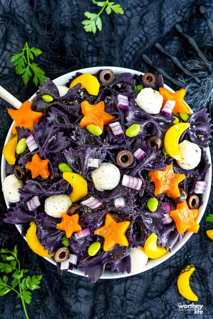 black pasta salad with vegetables in shapes of stars and moons with mozzarella mini balls