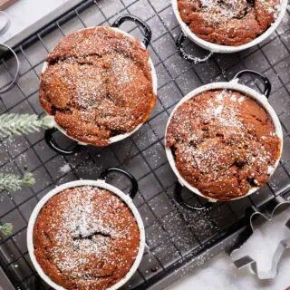Overhead view of gingerbread pudding cakes in ramekins on a wire rack.