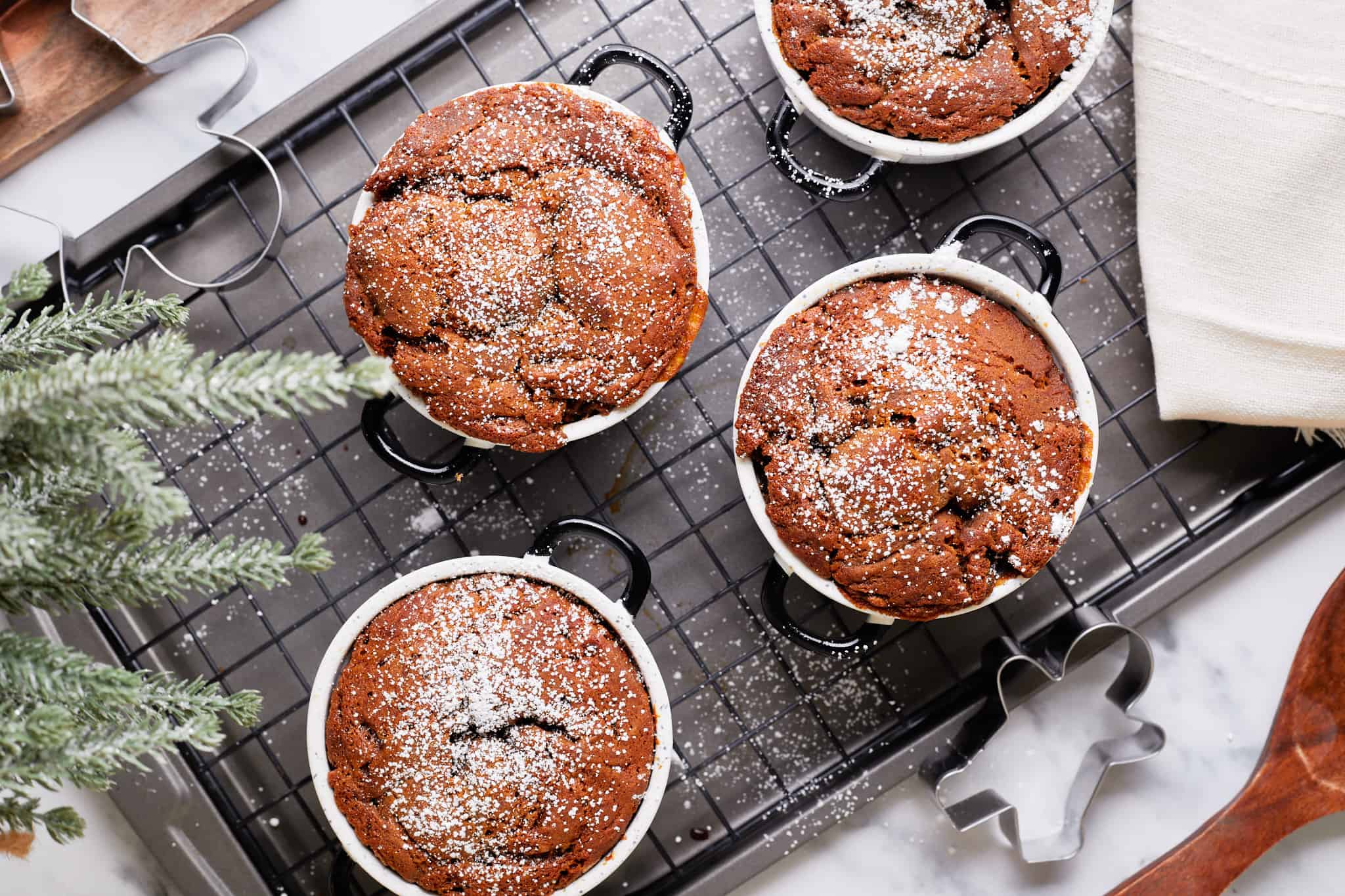 Overhead view of gingerbread pudding cakes in ramekins on a wire rack.