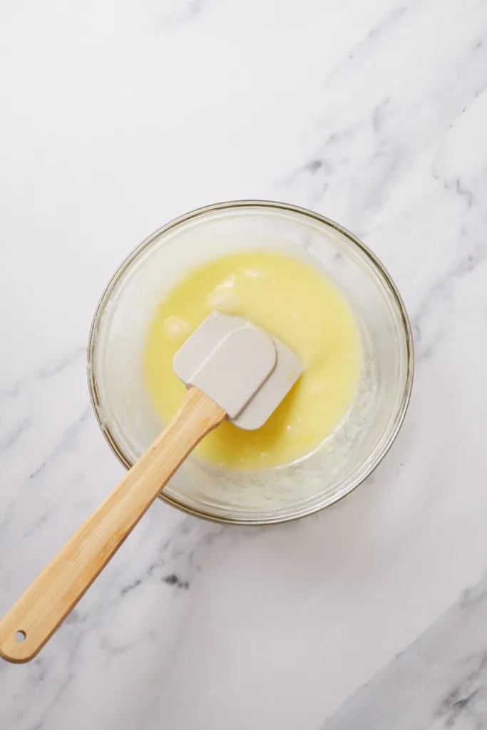 Mixing bowl with rubber spatula and melted butter and sugar mixture. 