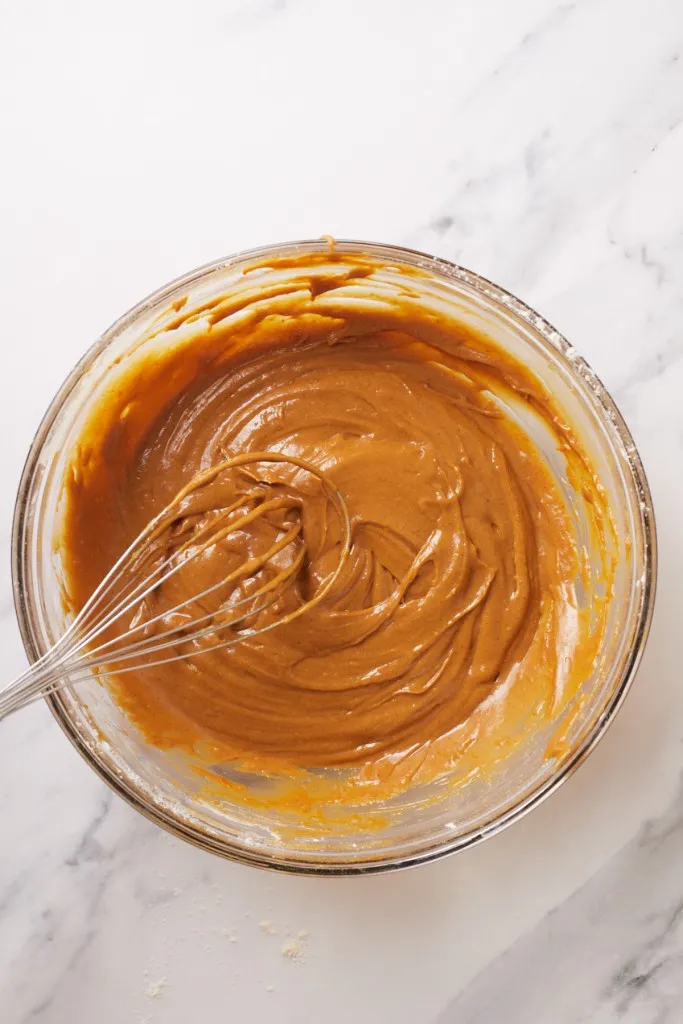Bowl with gingerbread pudding cake batter and whisk.