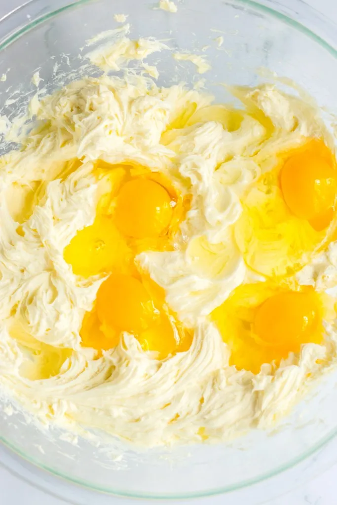 Twix cheesecake filling ingredients in a large glass mixing bowl.