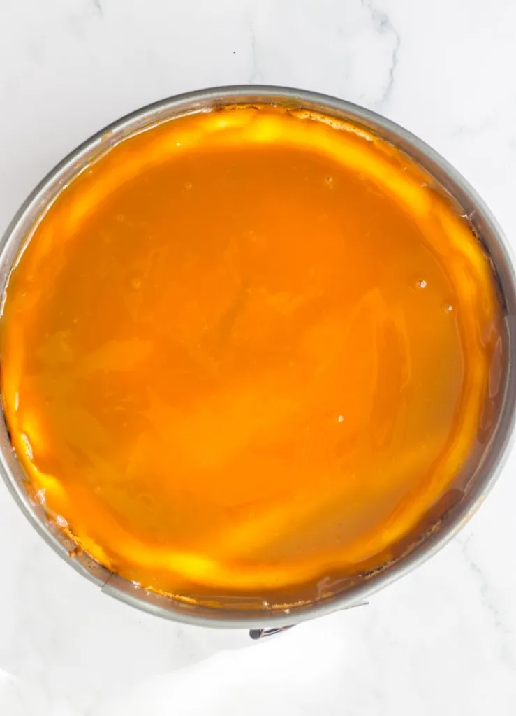 Baked Twix cheesecake with caramel sauce spread over the top.