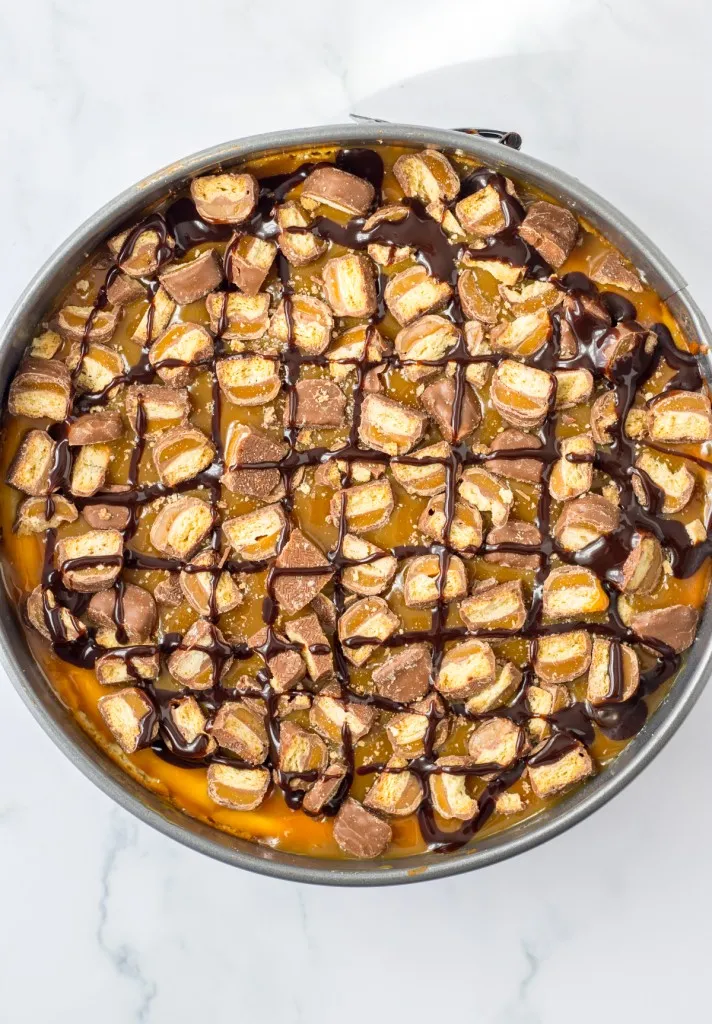 Twix cheesecake with diced Twix candy topping.