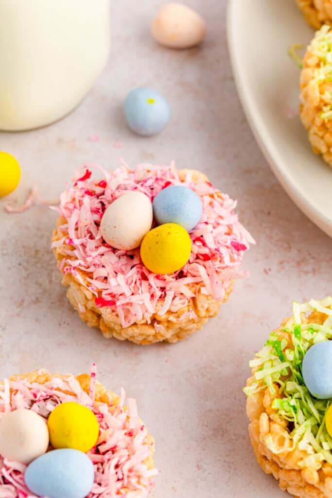 side view of easter rice krispies nests with green and pink coconut grass with chocolate eggs on top