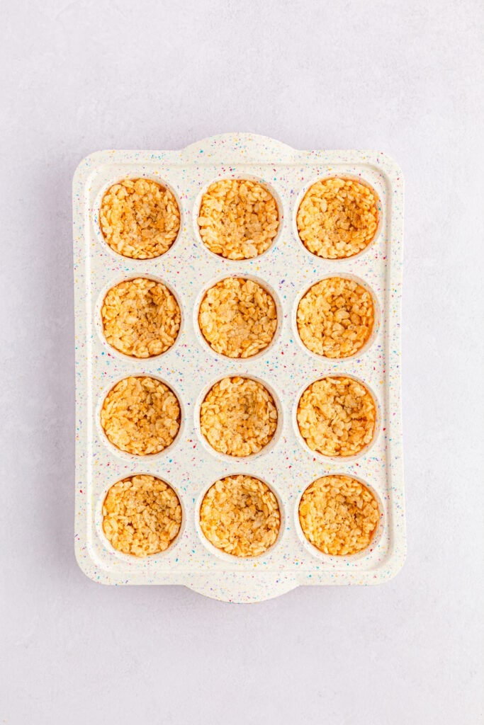 Mini muffin tray filled with Rice Krispies nest mixture.