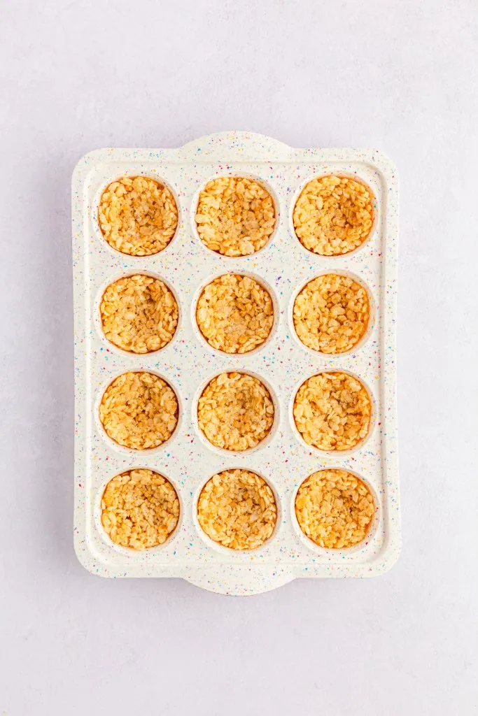 Mini muffin tray filled with Rice Krispies nest mixture.