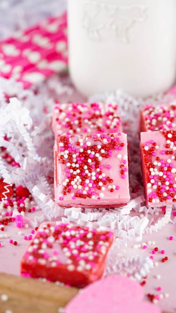 strawberry valentine's day chocolate fudge with a glass of milk on top of white paper confetti.